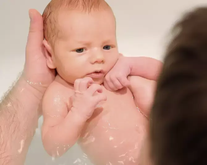 Padre aplicando las técnicas de baño con su bebé